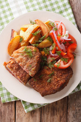 Fried Breaded rump steak with potato and vegetables close-up. vertical top view