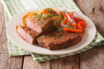 veal breaded rump steak and garnished with vegetables close-up. horizontal