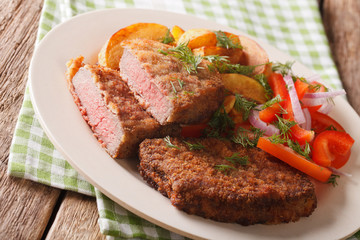 Breaded round steak and a side dish of vegetables close-up. horizontal
