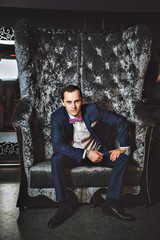 The man on the chair. In a blue suit, purple tie.