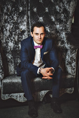The man on the chair. In a blue suit, purple tie.