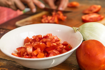 Mujer cortando tomate para una receta en casa. 