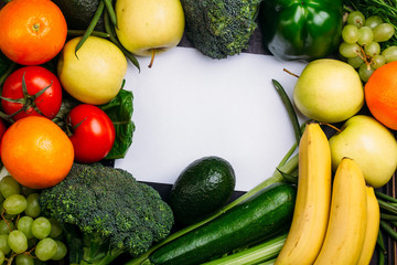 Food background of fresh fruit and vegetables bananas oranges apples grapes broccoli zucchini tomatoes on table Healthy lifestyle Top view Copy space in the middle