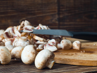 Fresh brown mushrooms and knife on chopping board. Side view