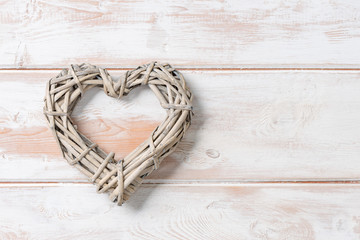 Fototapeta premium Wicker Rattan Heart on Wooden Panel with Copy Space