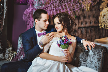 Wedding day. The bride and groom in a luxurious interior in lavender color. Wedding emotions. Beautiful bride and elegant groom at the ceremony.