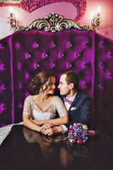 Wedding day. The bride and groom in a luxurious interior in lavender color. Wedding emotions. Beautiful bride and elegant groom at the ceremony.