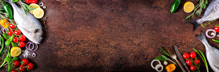Dorada, fresh fish with vegetable, lemon, herbs, onion, paprika, cherry tomatoes, onion, salton dark vintage background. Copy space. Banner