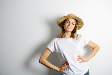 Joyful girl in a straw hat standing hands on waist