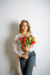 Feminine sweet young woman standing with a bouquet of bright tul