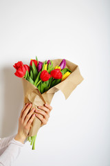 Bright bouquet of colored tulips in female hands, a good gift on