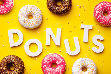 Flat lay donuts and letters on a yellow background. Top view