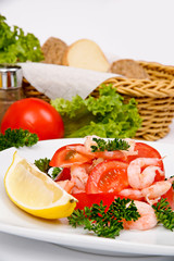 Salad with shrimp and tomatoes on a white plate with a serving