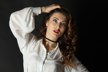 Beautiful girl model posing in a white blouse on a black background.