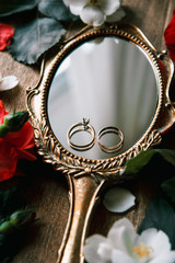 Beautiful wedding rings on a vintage mirror with flowers