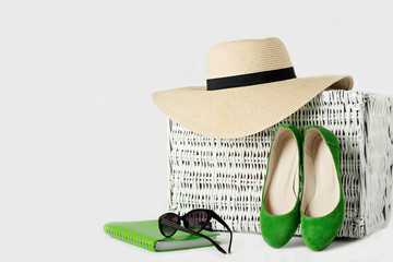 White wicker suitcase, womens hat, sunglasses, green shoes and n