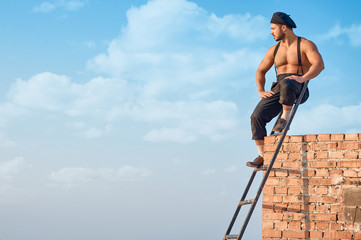 Builder leaning on brick wall on high.