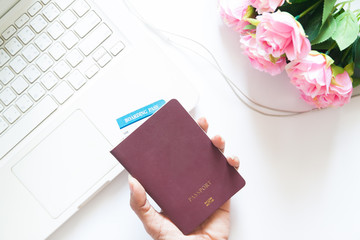 Obraz premium Woman hand holding passport and using laptop with pink rose, Ove