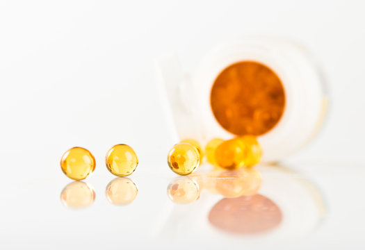 shiny yellow vitamin e fish oil capsule spilling out of pill bot