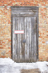 wooden plank door with metal plate for text, brick wall background