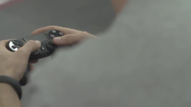 A gamer plays a game on a wireless controller. Playing Video Games. Male hands playing arcade video game with a corded game controller. Hands close-up.