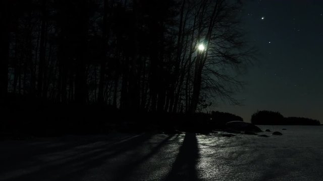 Moon rising time-lapse by a frozen lake