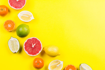 Several kinds of whole and cut citrus on a yellow background