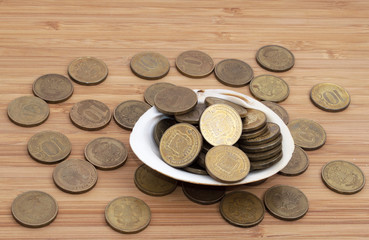 A sea shell with coins inside on wooden table 
