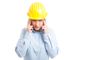 Female engineer wearing helmet making head ache gesture
