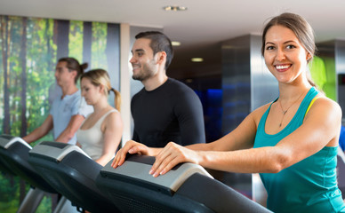 Fototapeta na wymiar Group of people doing cardio on treadmills in fitness club