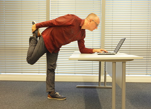 Leg Exercise During Office Work - Standing Middle Age Balding Man In Eyeglasses Man Reading At Laptop In His Office