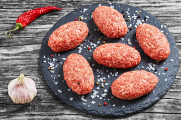 fresh ground raw meat cutlets on slate plate