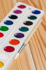 watercolors and brush on a wooden background