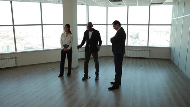 The New Office Will Bring You Success/Businessman, owner or a lessor show the buyer, lessee new office space. The room is completely empty, with large, bright windows, and high ceiling