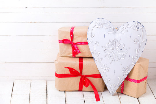 Festive gift boxes  and  big decorative heart on white wooden ba