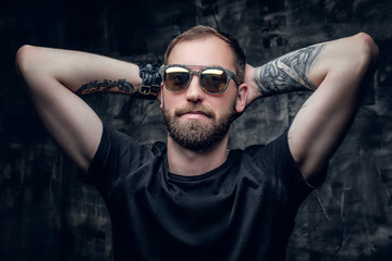 A man in sunglasses with tattoo on his arm.