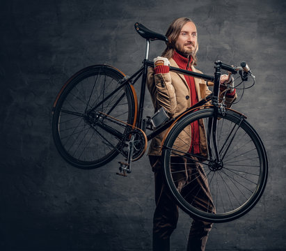 A man holds bicycle on his shoulder.