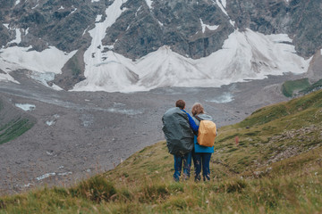 Man and woman standing and hugging on the top of the mountain, a