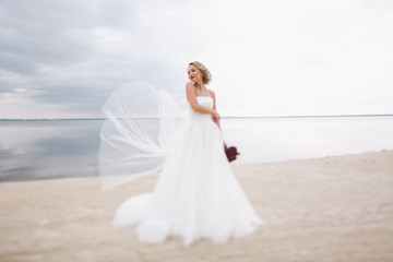 Fototapeta na wymiar Portrait of beautiful bride in wedding day on the shore of the sea.