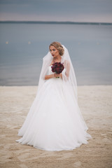 Fototapeta na wymiar Portrait of beautiful bride in wedding day on the shore of the sea.