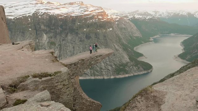 Three friends on the Trolltunga. Norway, sunset