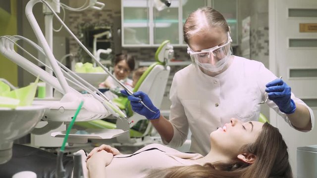 Dentist check up girl's teeth, doctor teaches a child to brush teeth on a background. 4k footage. Dental clinic.
