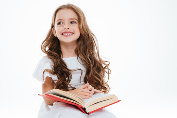 Smiling little girl sitting and reading book