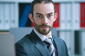 Businessman peeping from behind the monitor, looking into the camera