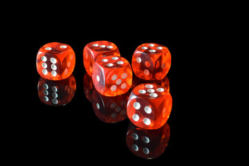 Five transparent red dice on black surface with reflection.