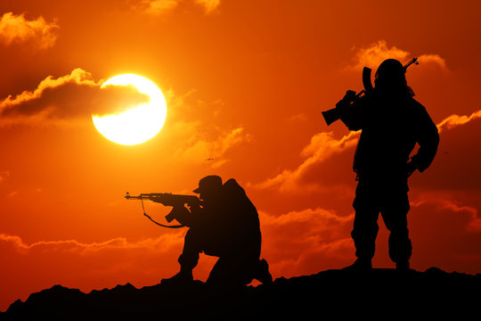 Two men shot dead a soldier holding a gun and Vit mountain piktureskie bakkdrop al sunset