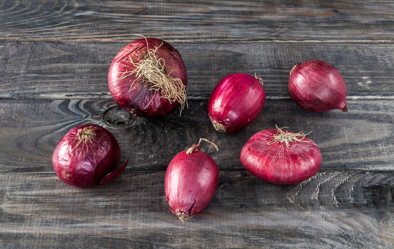 Different kind of red onion on old dark grey rustic wooden table background. Fresh organic vegetables and spices set.  Kitchen and cooking concept. Ingredients for soup, salad, dinner menu.
