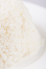 Plate with white boiled rice on gray background.