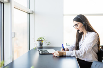 Young lady work in call center and make notice in book