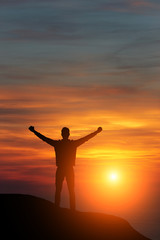 Fototapeta premium man against the sea standing on a mountain top looking into the distance